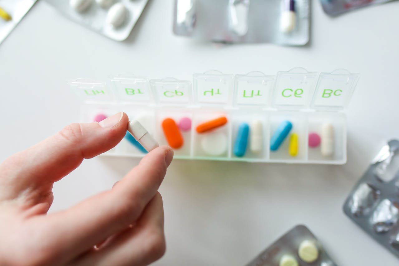 Mastering the First Impression: Your intriguing post title goes here Close-up of a hand selecting a pill from a weekly pill organizer, illustrating daily health and medication routines.